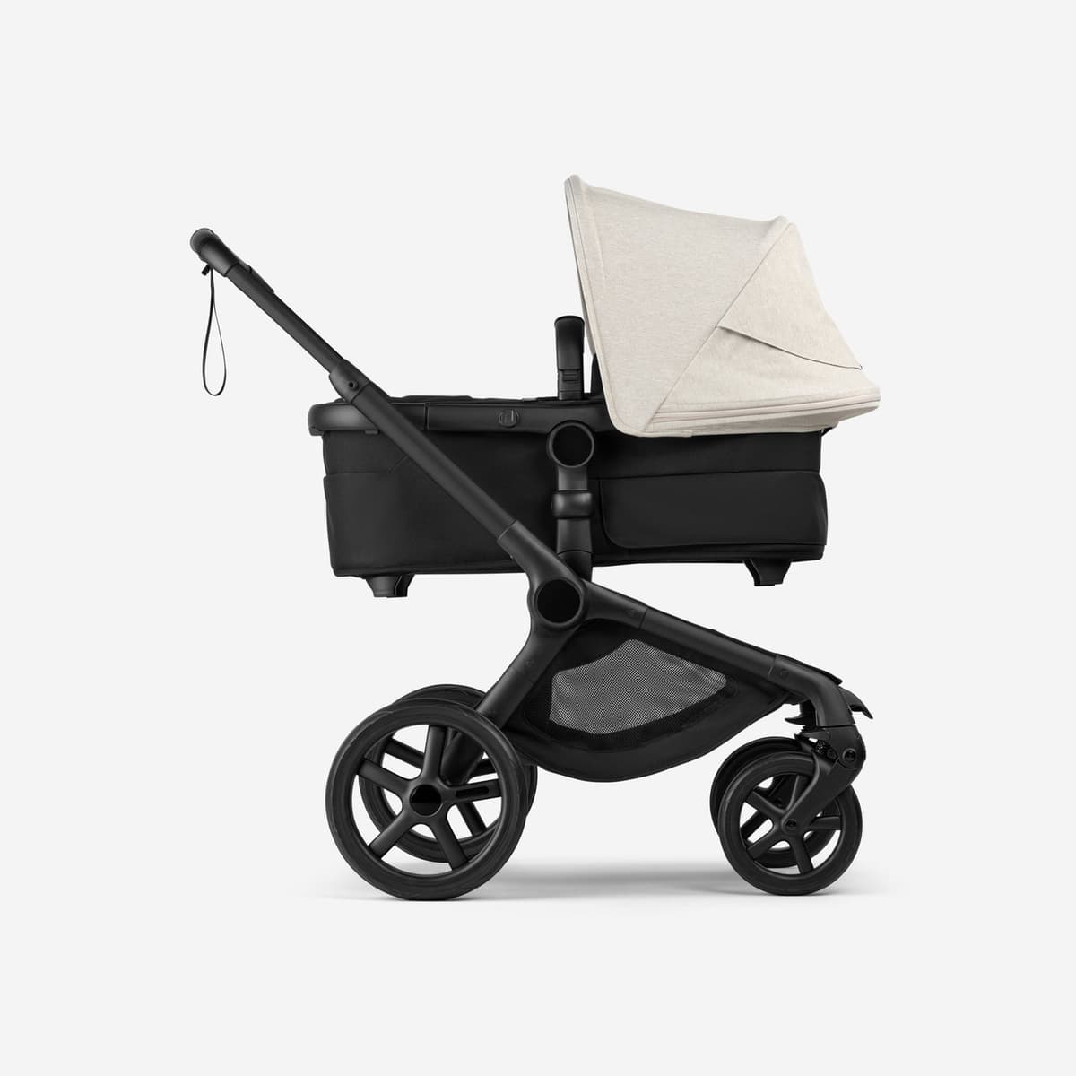 Bugaboo Fox 5 stroller in midnight black with bassinet on a tree-lined city street