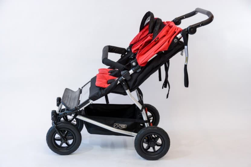 Mountain Buggy Duet side-by-side double stroller in black with both seats, on a narrow urban sidewalk