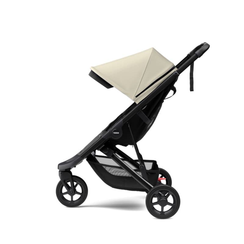 Thule Spring stroller in forest green on a city path with Thule's signature outdoor design language