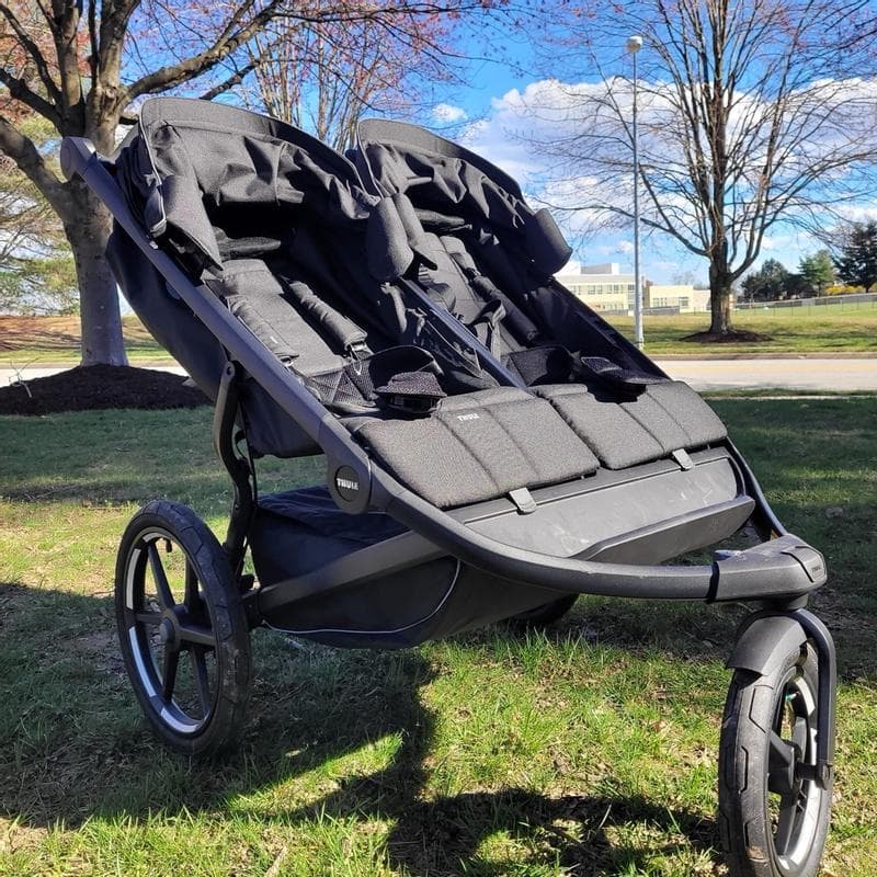 Thule Urban Glide 3 Double tandem jogging stroller in black on a running trail with two children