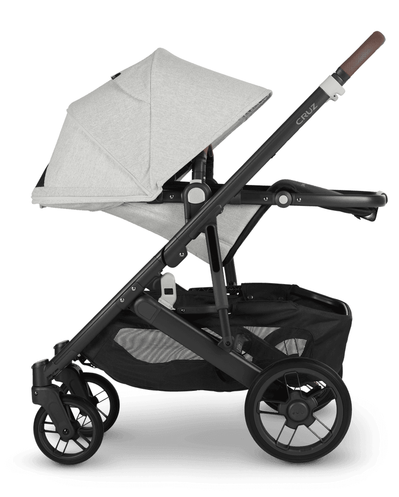 UPPAbaby Cruz V2 stroller in charcoal with toddler seat forward-facing on a city street