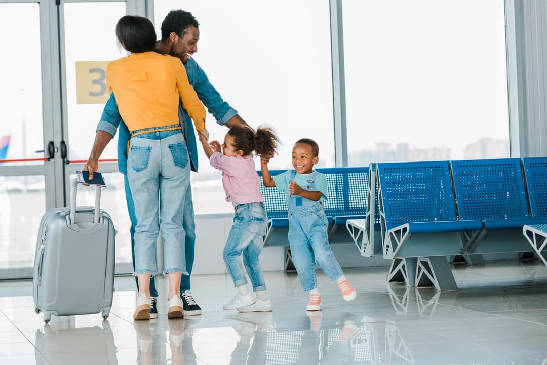 Parent researching airline policies on their phone while their toddler sleeps on their shoulder at the airport