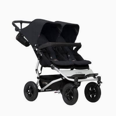 Mountain Buggy Duet side-by-side double stroller in black with both seats, on a narrow urban sidewalk