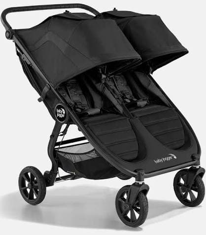 Baby Jogger City Mini GT2 Double stroller in black on a city sidewalk with two children seated