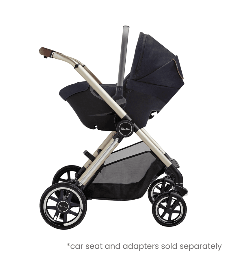 Silver Cross Reef 2 stroller in glacier white with bassinet on a park path