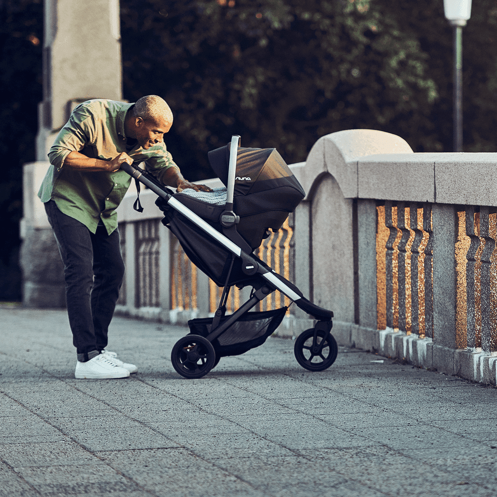Thule Spring stroller in forest green on a city path with Thule's signature outdoor design language