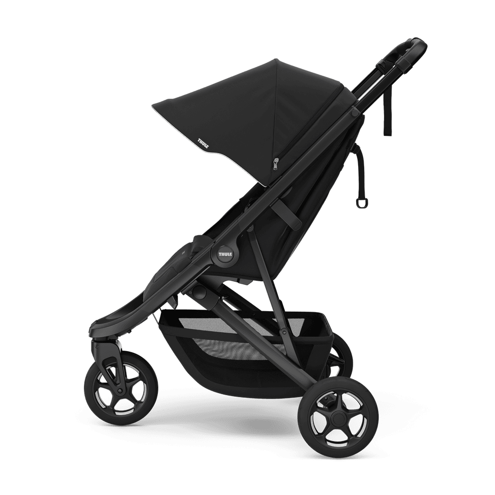 Thule Spring stroller in forest green on a city path with Thule's signature outdoor design language